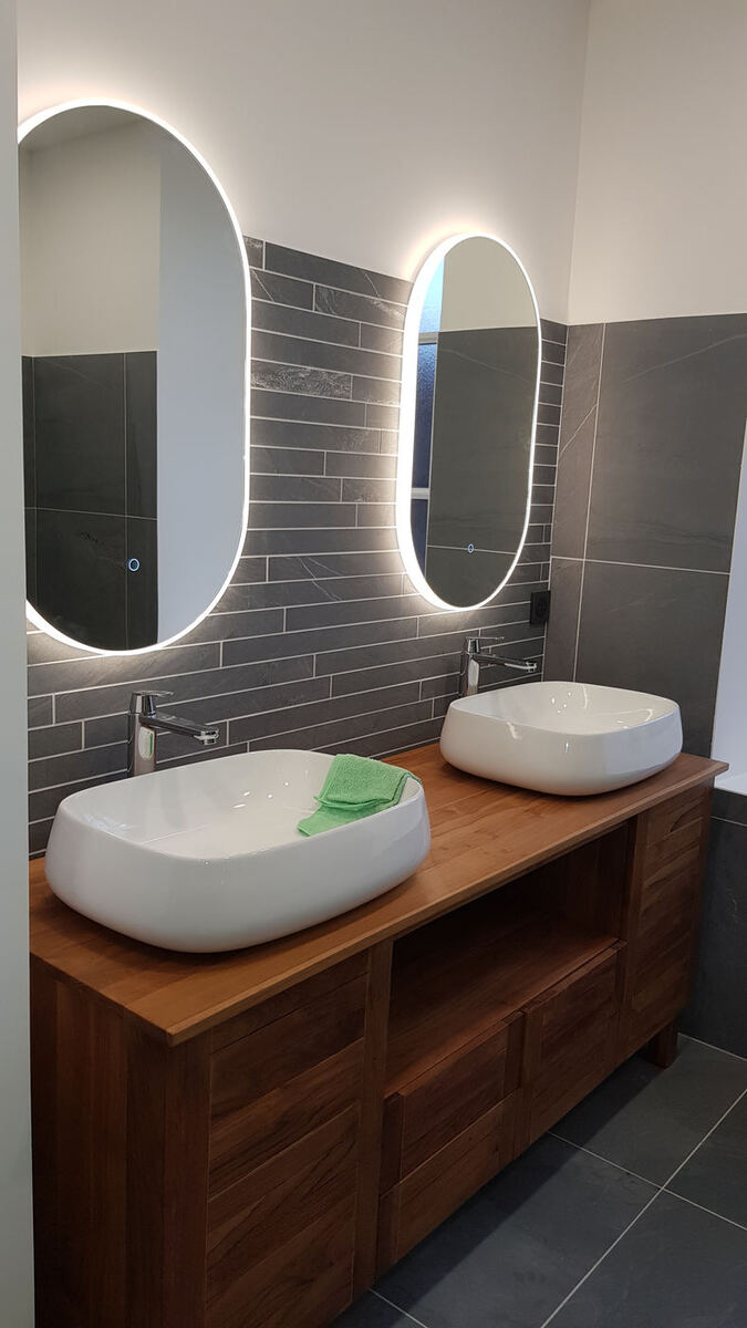 Salle de bains rénovée avec double vasque et miroirs lumineux